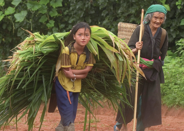 Old lady with staff and young girl with load of leaves