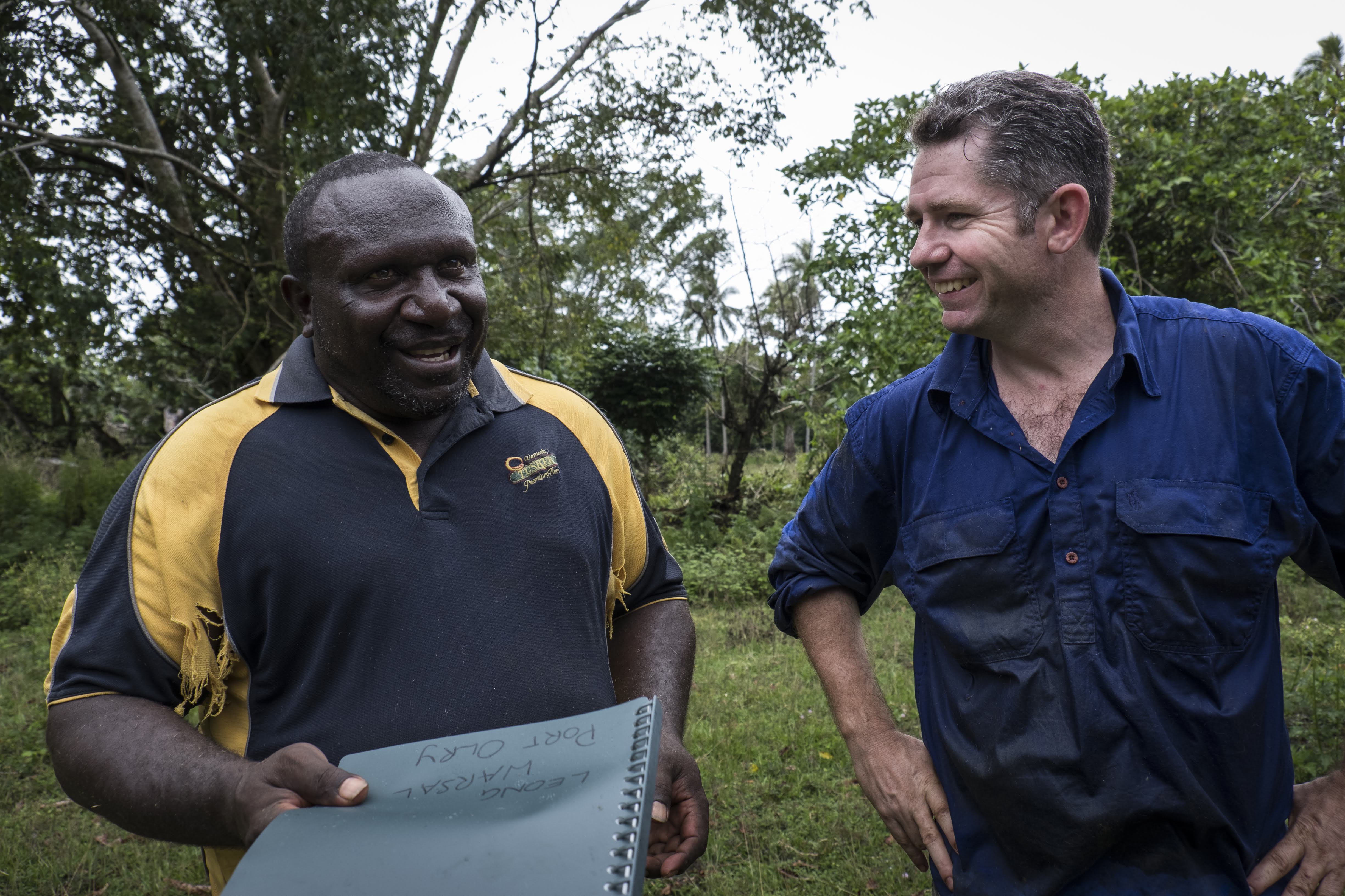 Simon Quigley from University of Queensland hands farmer Leon Warsaw Katty a Bisnis Blong Buluk folder with extension material and a list of Leon's cattle that were weighed and tagged inside the Bisnis Blong Buluk mobile cattle crush