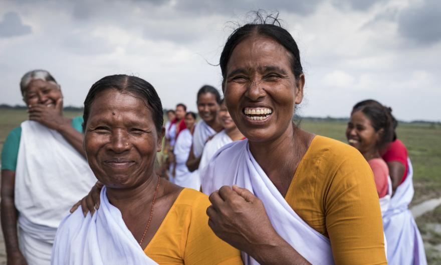 Two women dressed in colourful saris smile at the camera